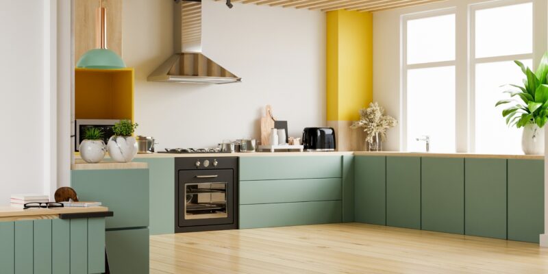 A kitchen with teal cabinet colors and natural light.
